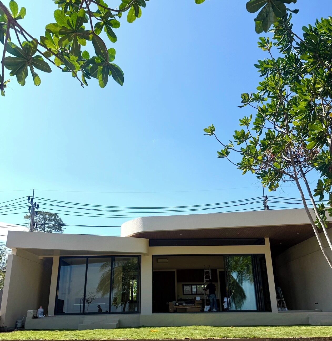 A modern house with large glass windows, a flat roof, and a visible power line.