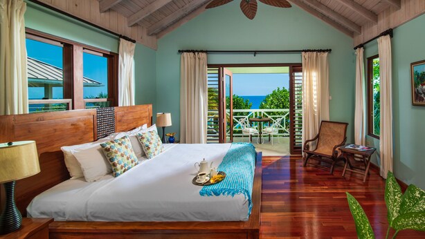A spacious bedroom with a large bed, wooden headboard, and a ceiling fan.