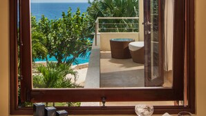 A bathroom with a bathtub, a window overlooking a pool and greenery, and a glass of red wine on the counter. - Little Waters on the Cliff (Negril)