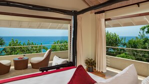 A balcony with a view of the ocean, wicker furniture, and a bed with white and red pillows. - Little Waters on the Cliff (Negril)