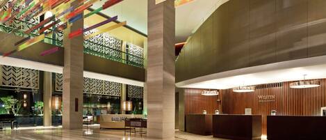 A spacious lobby with a modern design, featuring a reception desk, seating area, and a decorative ceiling with colorful elements.