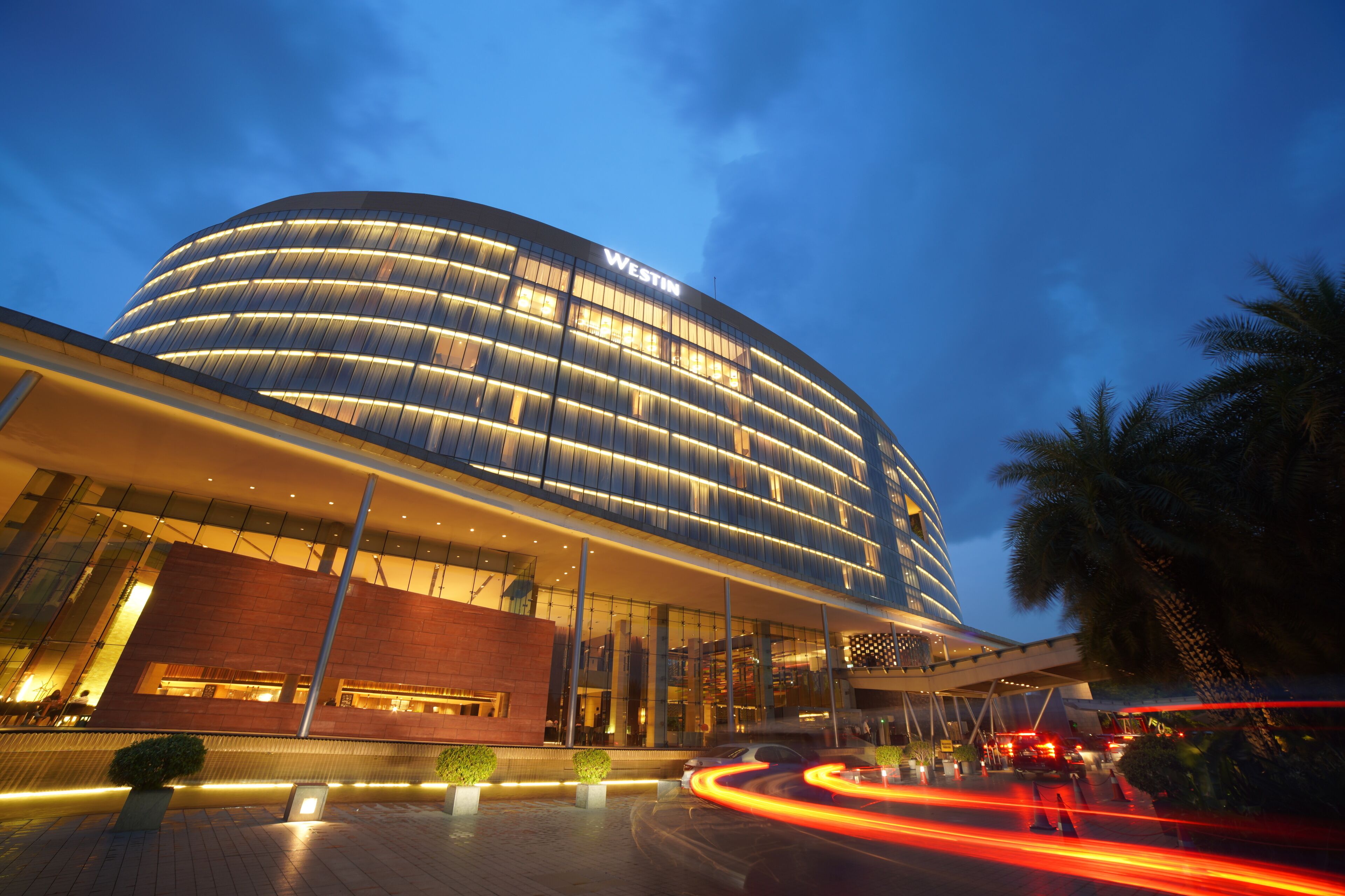 A modern hotel with a curved facade, large glass windows, and a prominent "WESTIN" sign.