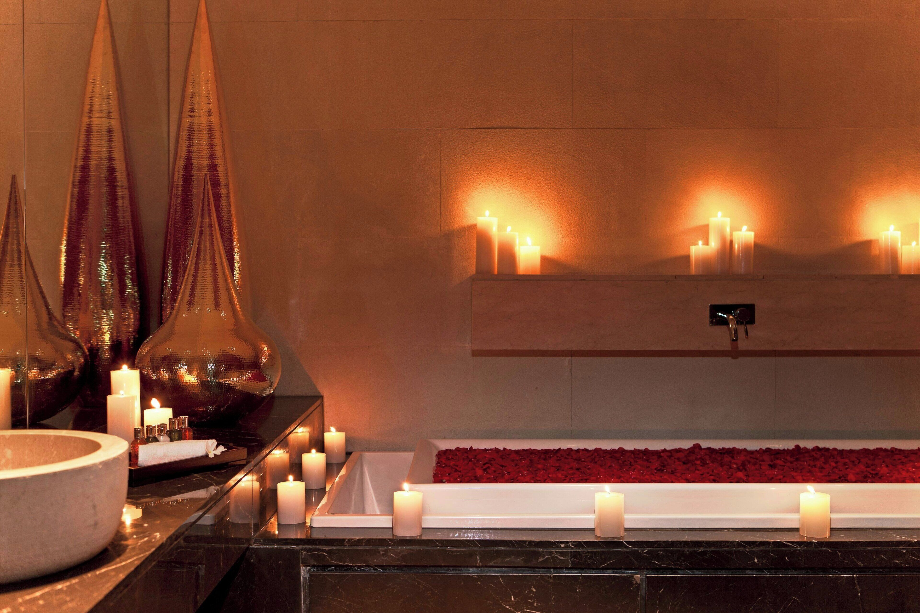 Zona de spa con velas, una cuenca de piedra y un arreglo floral.