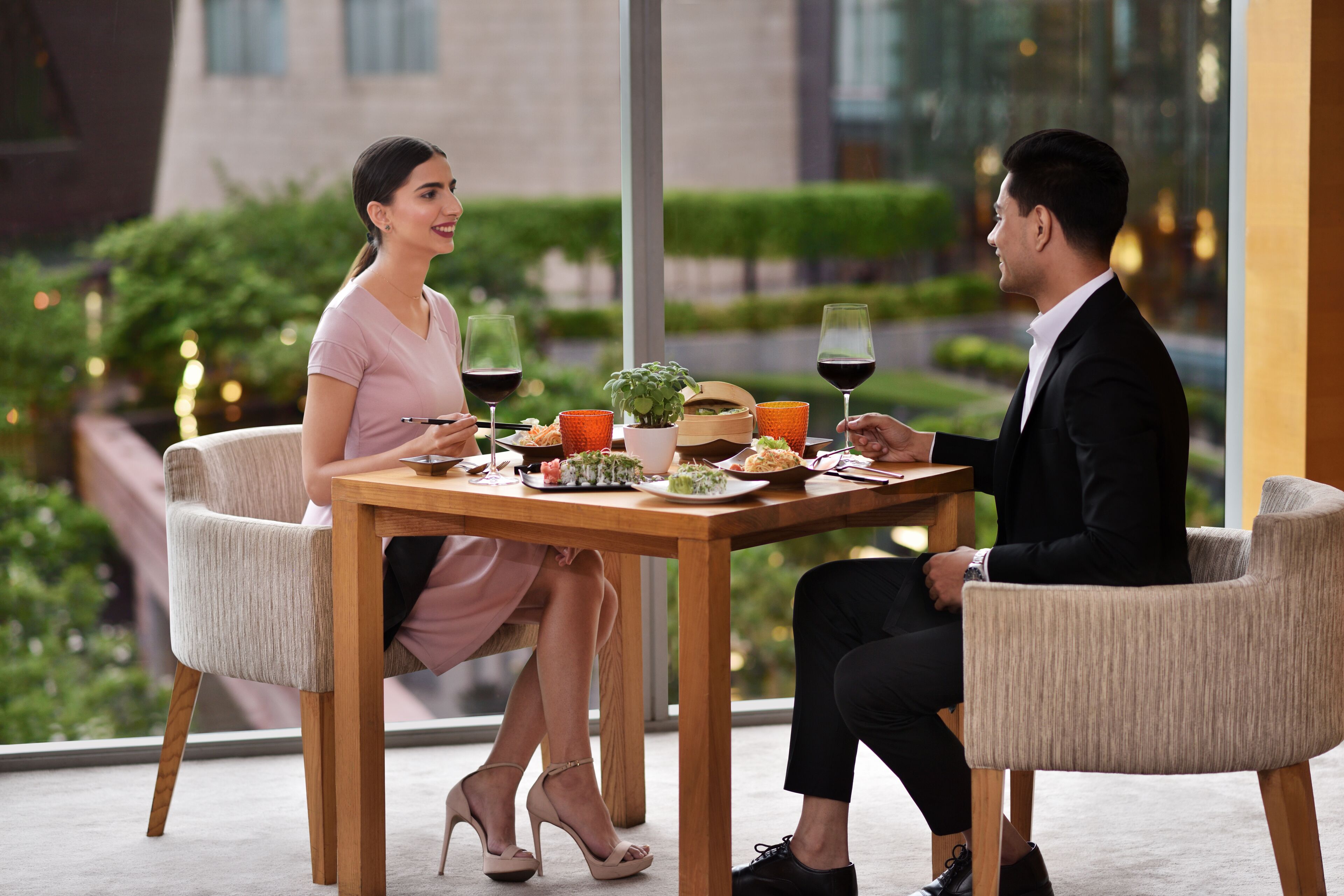 A couple dining at a table with a view of the outdoors.