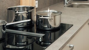 Una cocina con estufa, ollas y un juego de cuchillos.