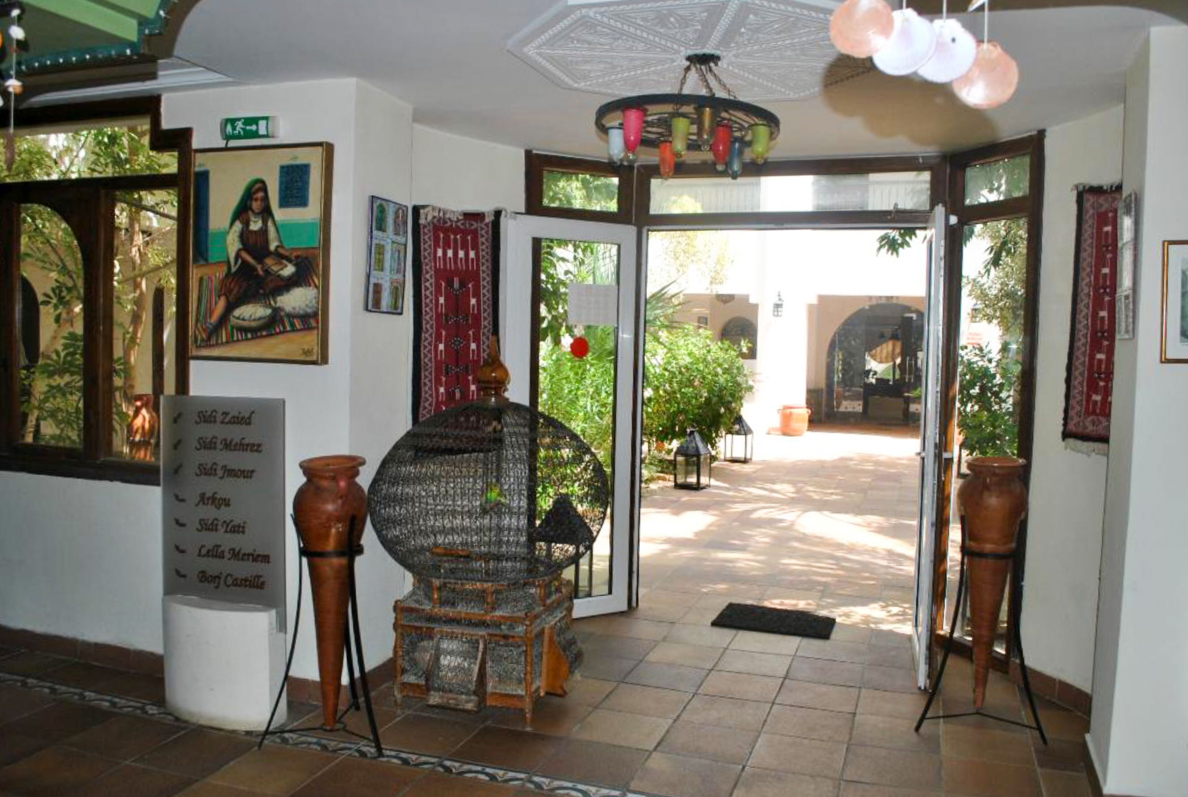 A traditional interior with a sign listing names, a large woven chair, and a view of the outside.