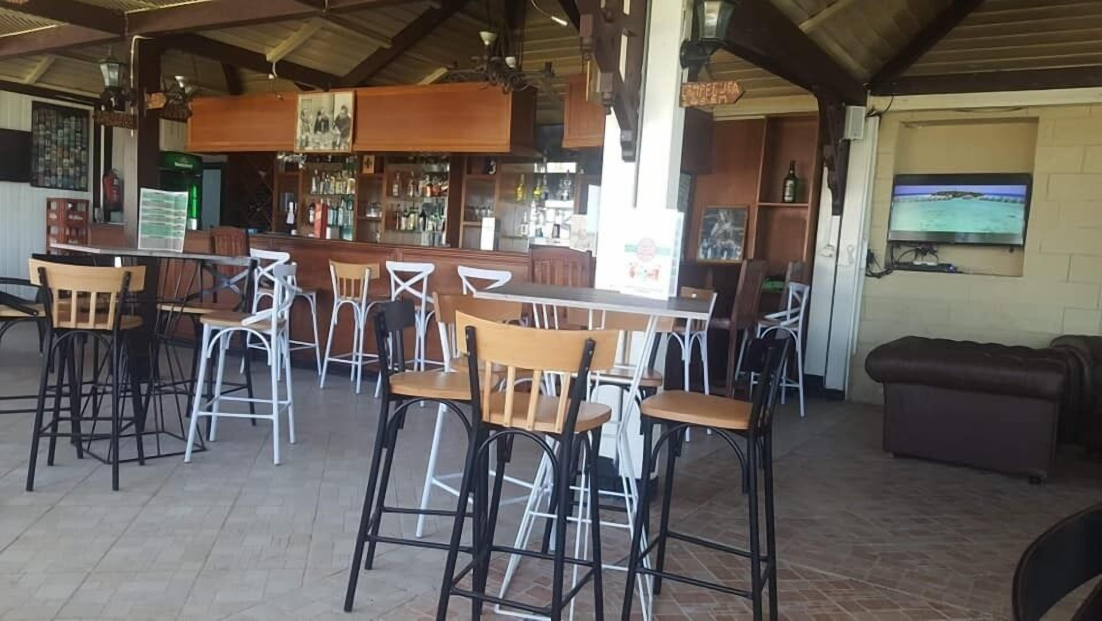 A bar area with multiple stools and tables, a counter with a menu, and a television mounted on the wall.