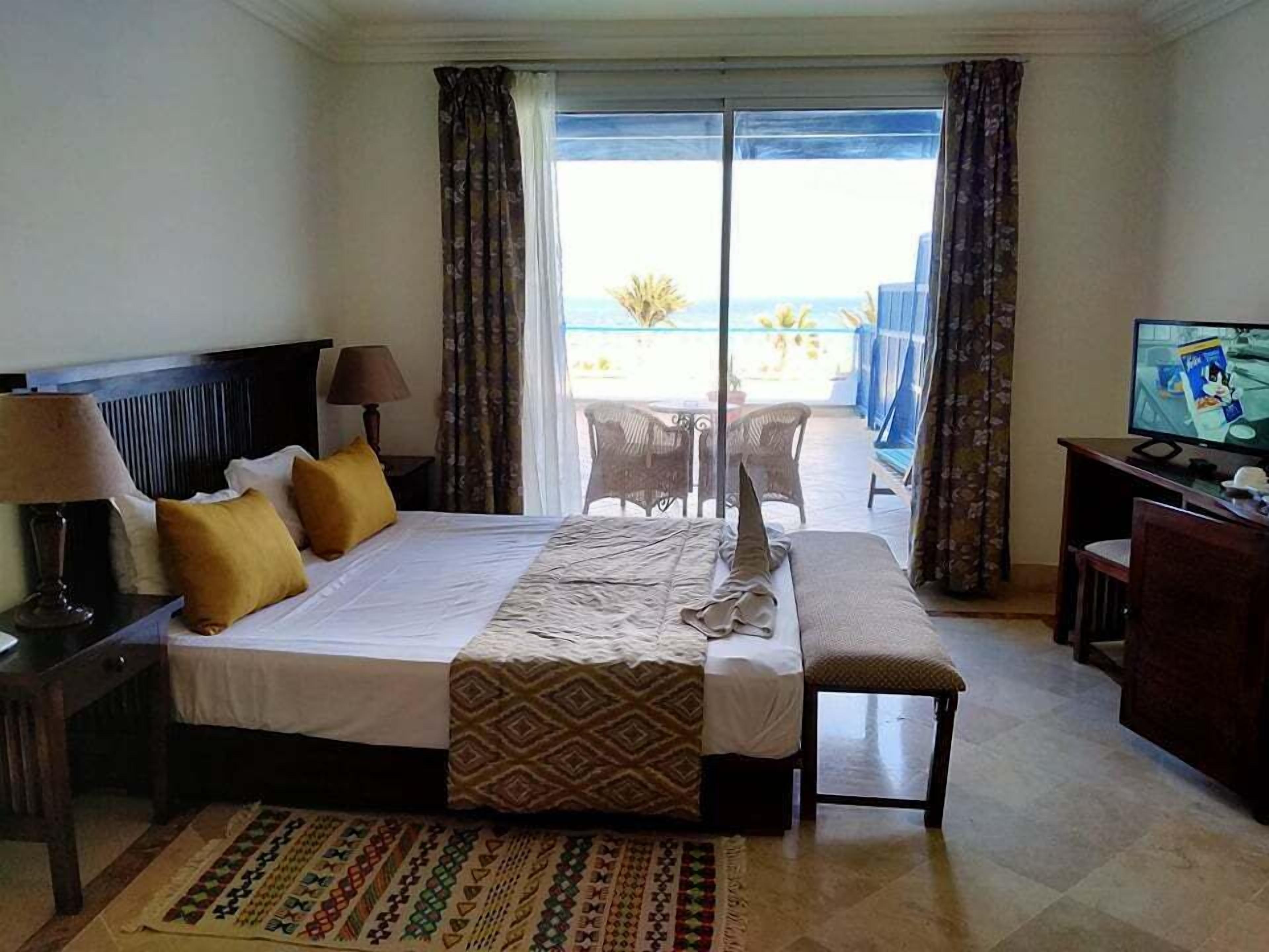 Una camera d'albergo con un letto, una scrivania, una TV e vista sull'oceano.