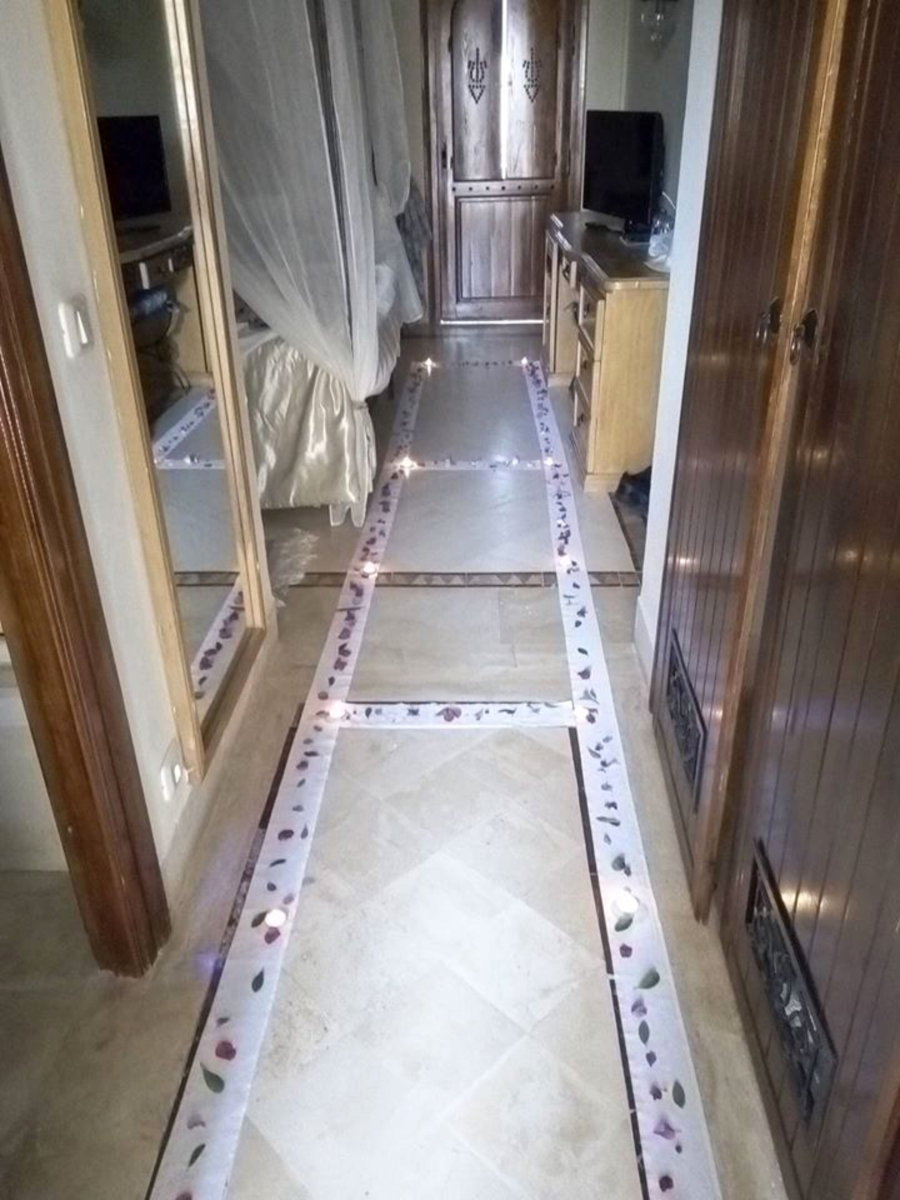 Un estrecho pasillo con piso de baldosas, una cama con dosel y armarios de madera.