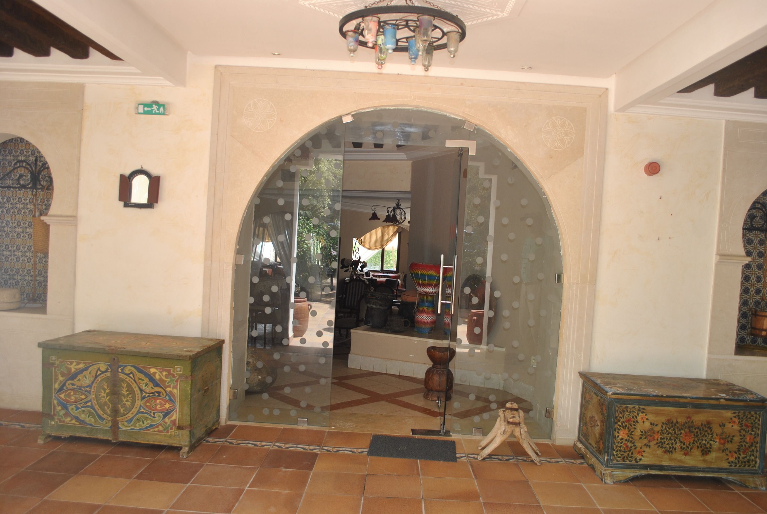 An interior with a large arched doorway, a tiled floor, and two ornate wooden chests.
