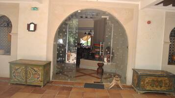 An interior with a large arched doorway, a tiled floor, and two ornate wooden chests.
