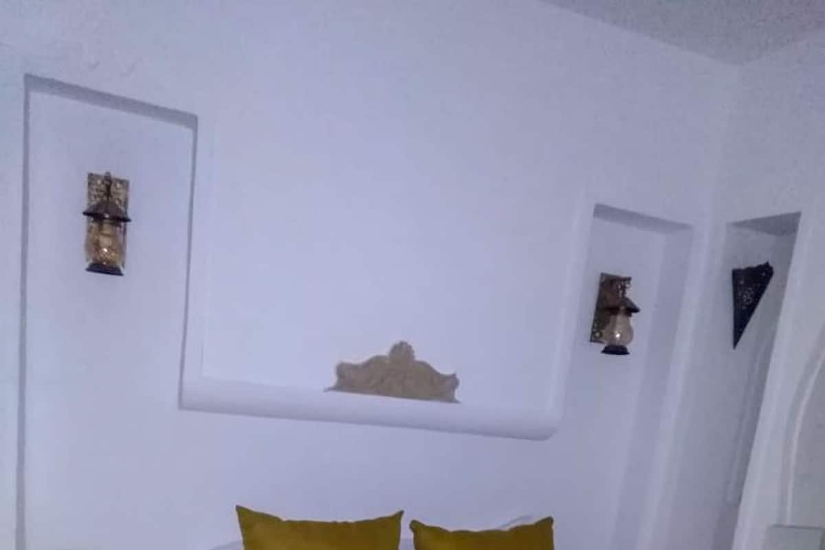 A hotel room with a bed, two pillows, a decorative wall piece, and a towel on the bed.