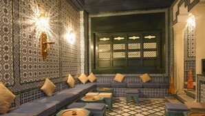 A traditional Moroccan interior with patterned tile walls, a low seating area with cushions, and a checkered floor. - Vincci Helios Beach (Aghir)