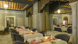 A dining area with tables set for multiple guests, featuring intricate tile work and a chandelier. - Vincci Helios Beach (Aghir)