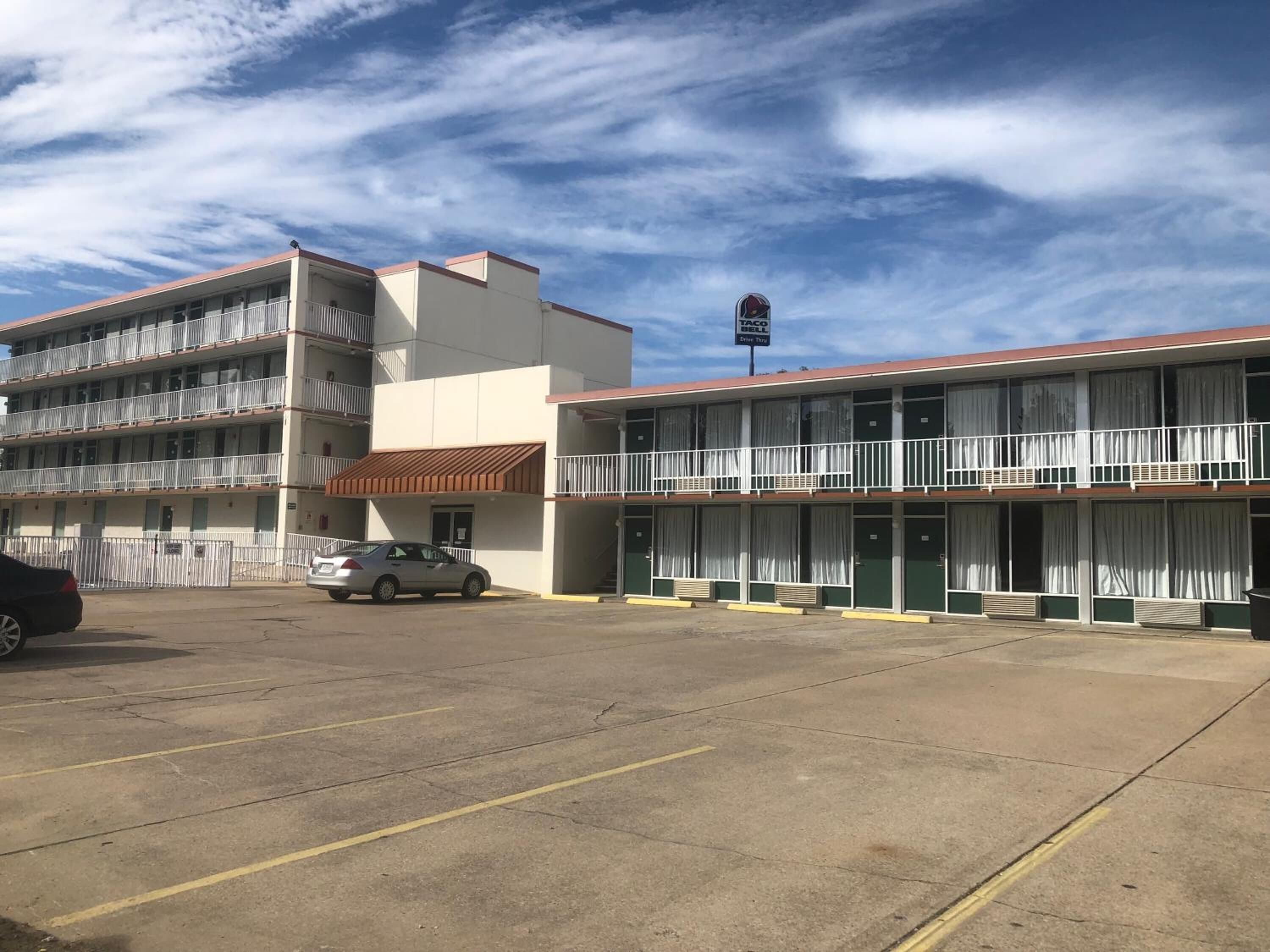 Een motel met meerdere verdiepingen, een parkeerplaats en een bord van Taco Bell.