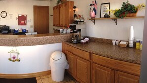 A kitchen with a granite countertop, a coffee machine, a clock, and a welcome sign. - Willow Tree Inn (Branson)