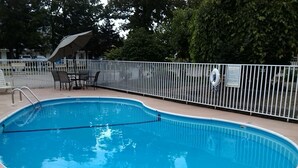 A swimming pool with a metal fence, a lifeguard chair, and a covered seating area. - Willow Tree Inn (Branson)
