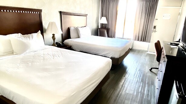 A hotel room with two beds, a desk, a chair, and a TV. - Willow Tree Inn (Branson)