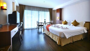 A hotel room with a bed, desk, chair, and a television. - Patong Palace Hotel (Patong)