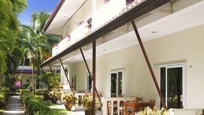 A two-story building with a covered patio area, outdoor seating, and potted plants. - Patong Palace Hotel (Patong)