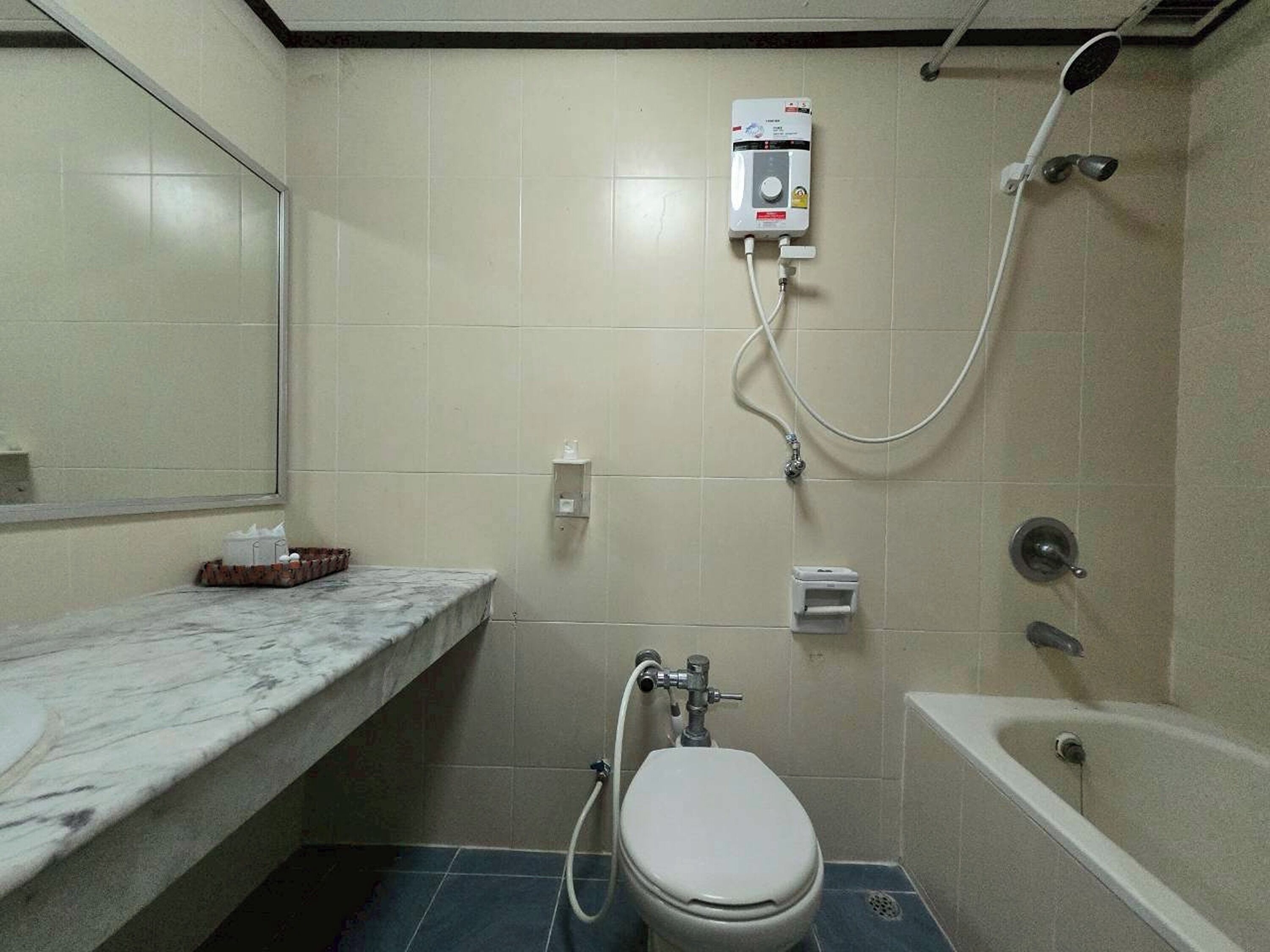 A small bathroom with a toilet, a shower, and a marble countertop.