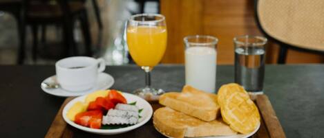 A breakfast tray with various dishes, including rice, shrimp, and vegetables, on a wooden table in a restaurant.
