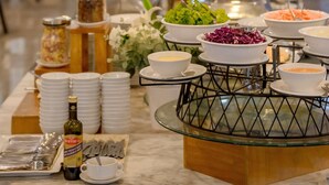 Montaje de bufé con diversos platos y aderezos, incluyendo una botella de vino Biertelli, dispuesto sobre una mesa de mármol.