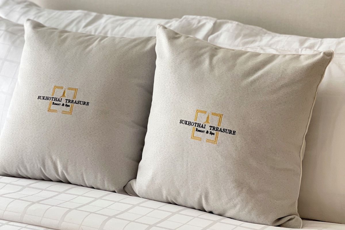 A sofa with two pillows featuring a logo and text.
