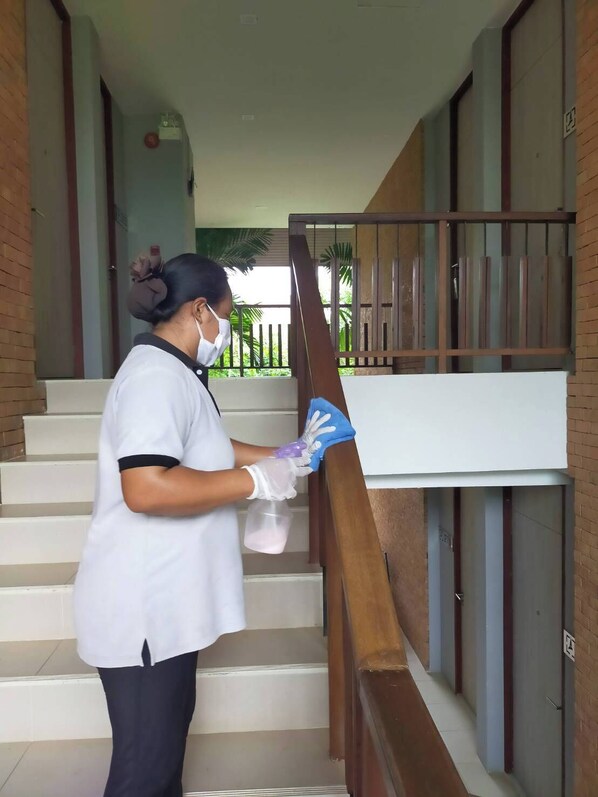 Una persona limpiando una escalera con un pulverizador y guantes.