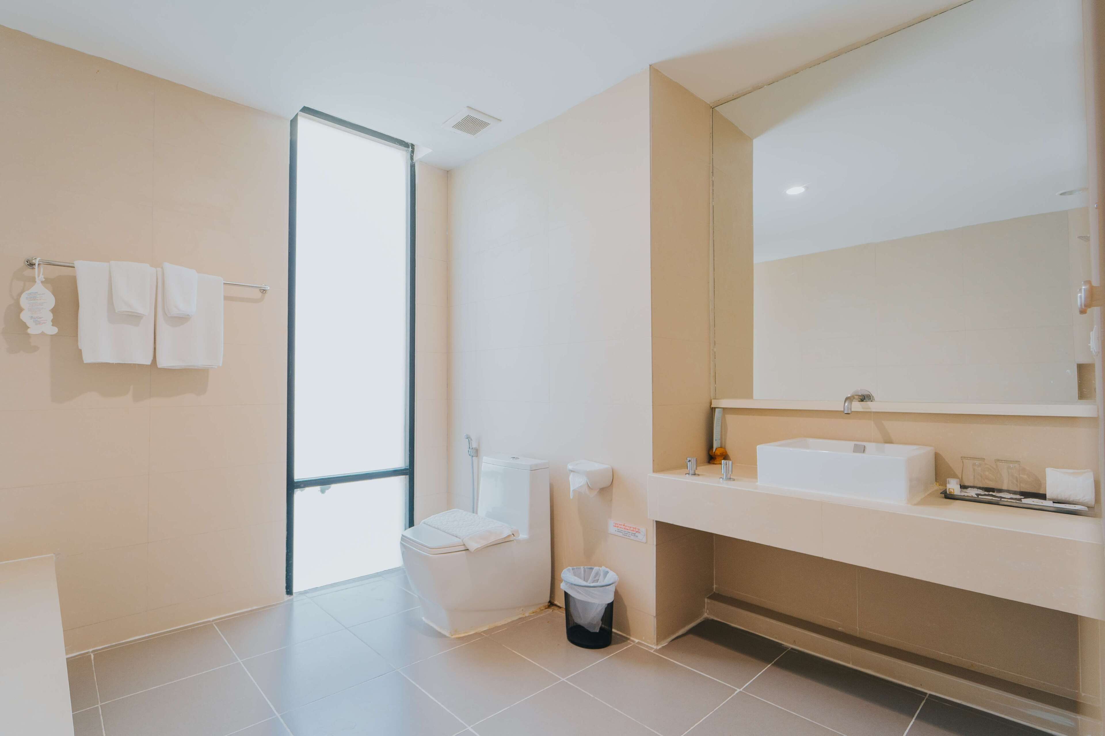 A modern bathroom with a toilet, sink, and large mirror.