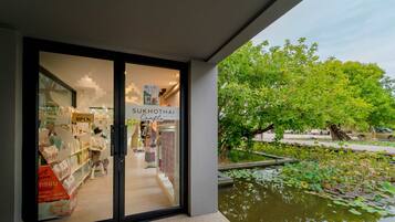 A storefront with a sign reading "SUKKHOTHAI Crafts" and a view of a pond with lily pads.