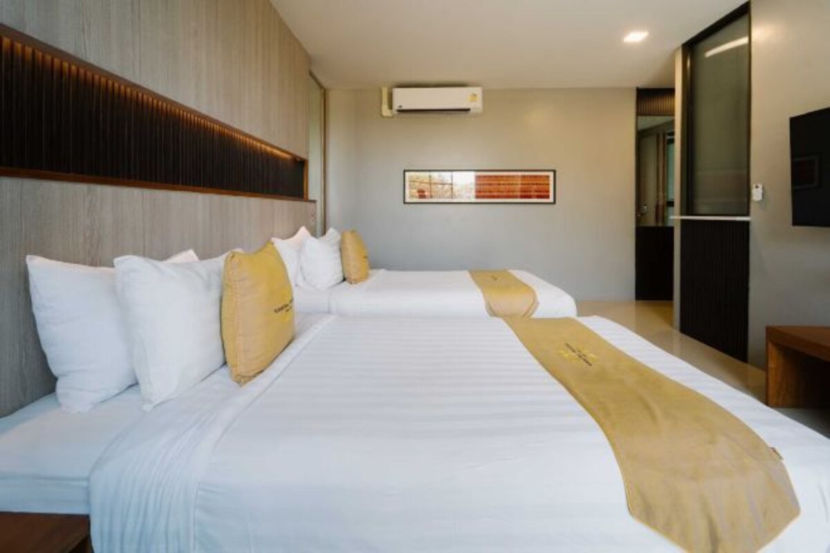 A hotel room with two beds, a wooden headboard, a framed picture on the wall, and a small table.