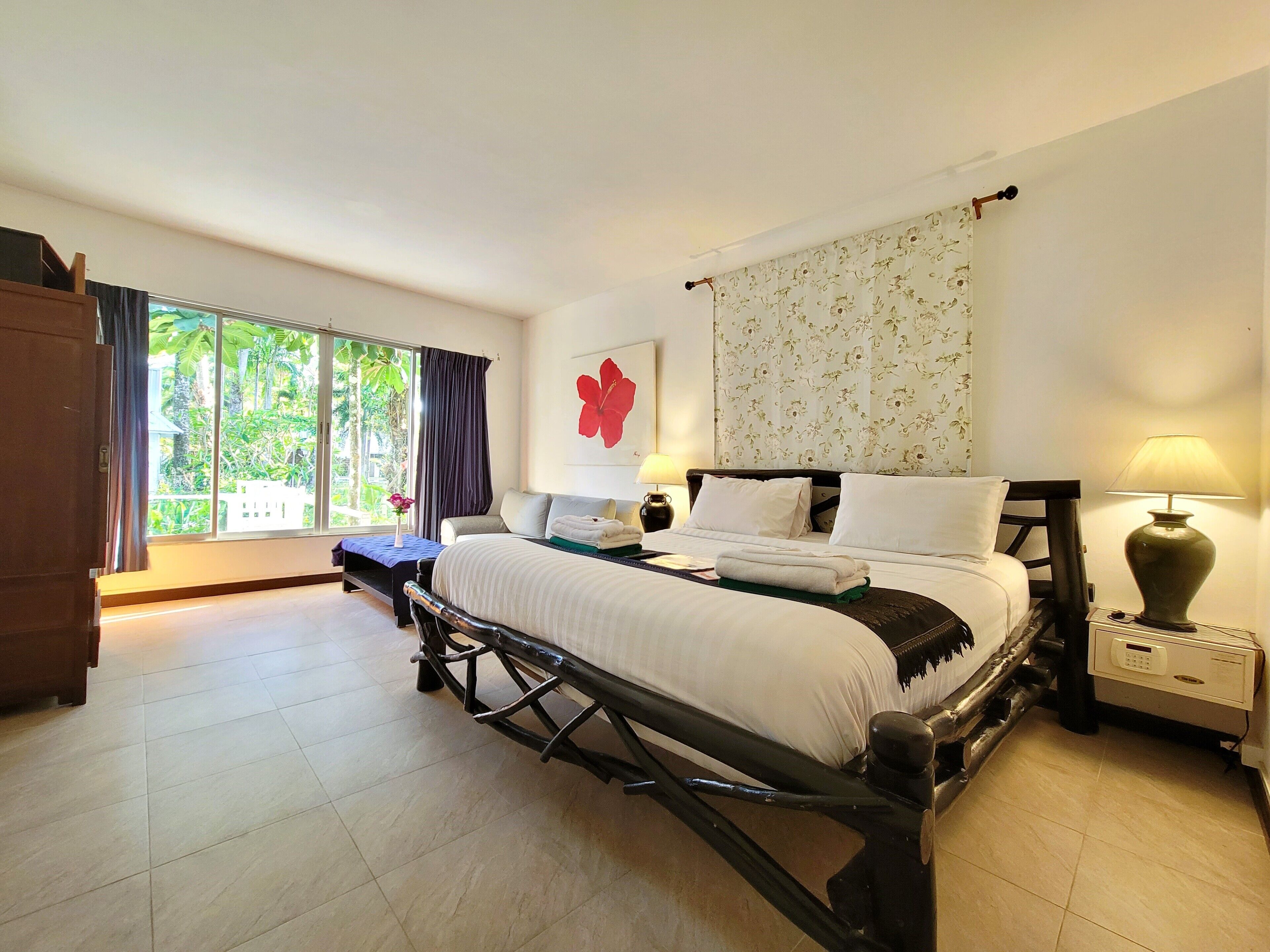 A hotel room with a bed, bedside tables, a desk, a chair, and a window with curtains.