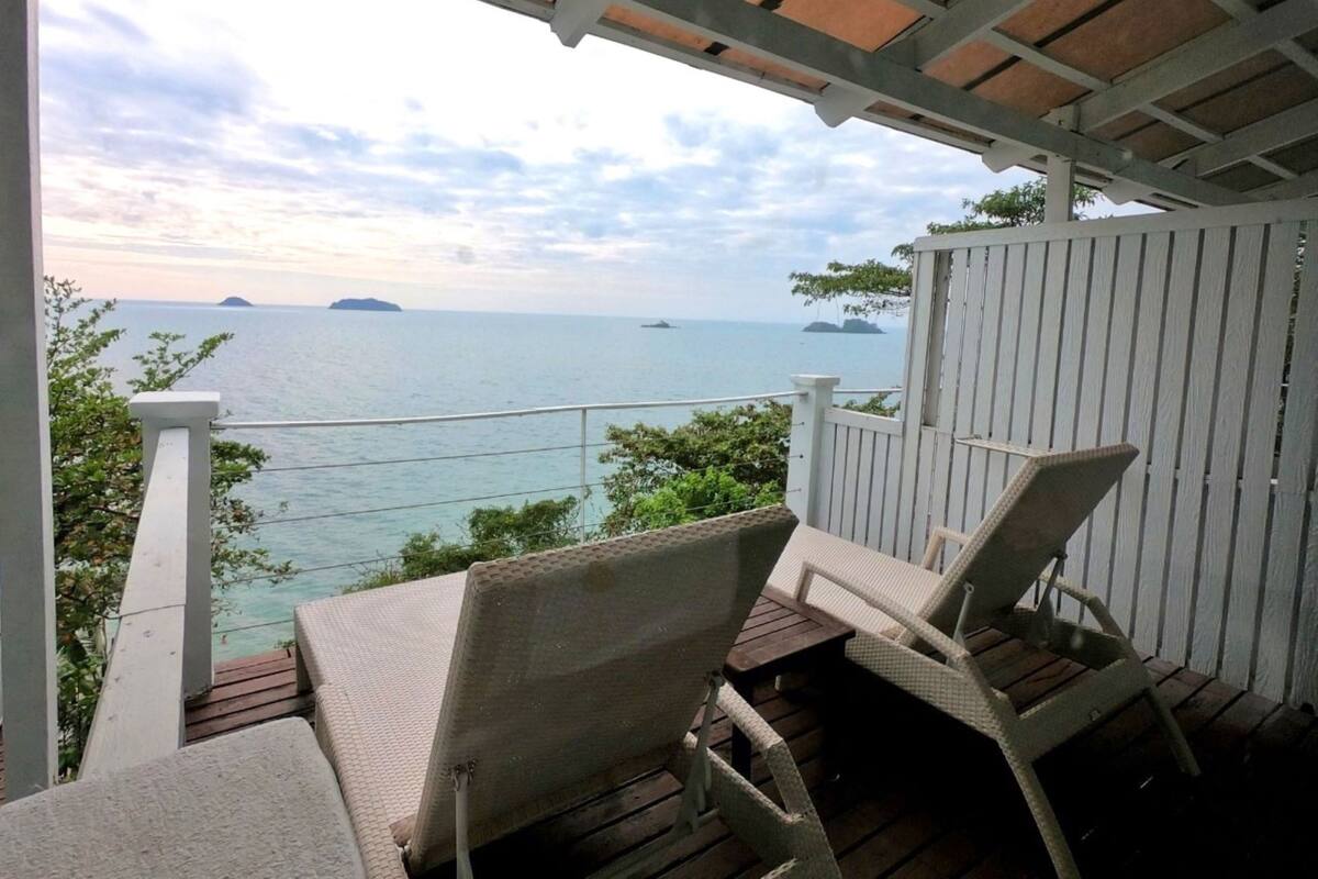 A covered outdoor seating area with a view of the sea and islands.