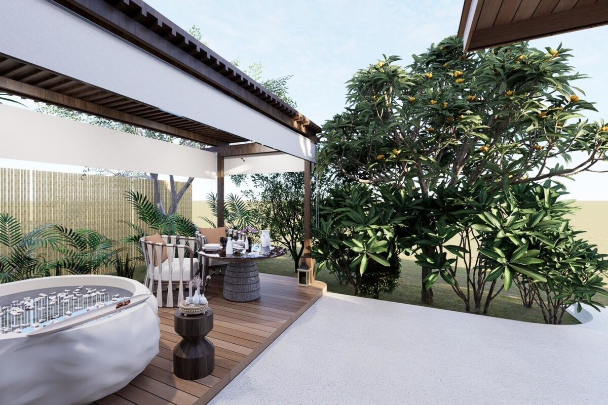 A modern outdoor patio with a wooden deck, a white cushioned seating area, and a variety of plants.