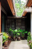 A traditional Japanese-style entrance with a thatched roof and potted plants.