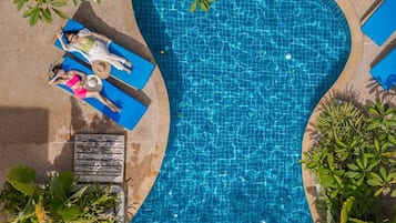 Relax by the pool surrounded by lush greenery and comfortable lounge chairs.