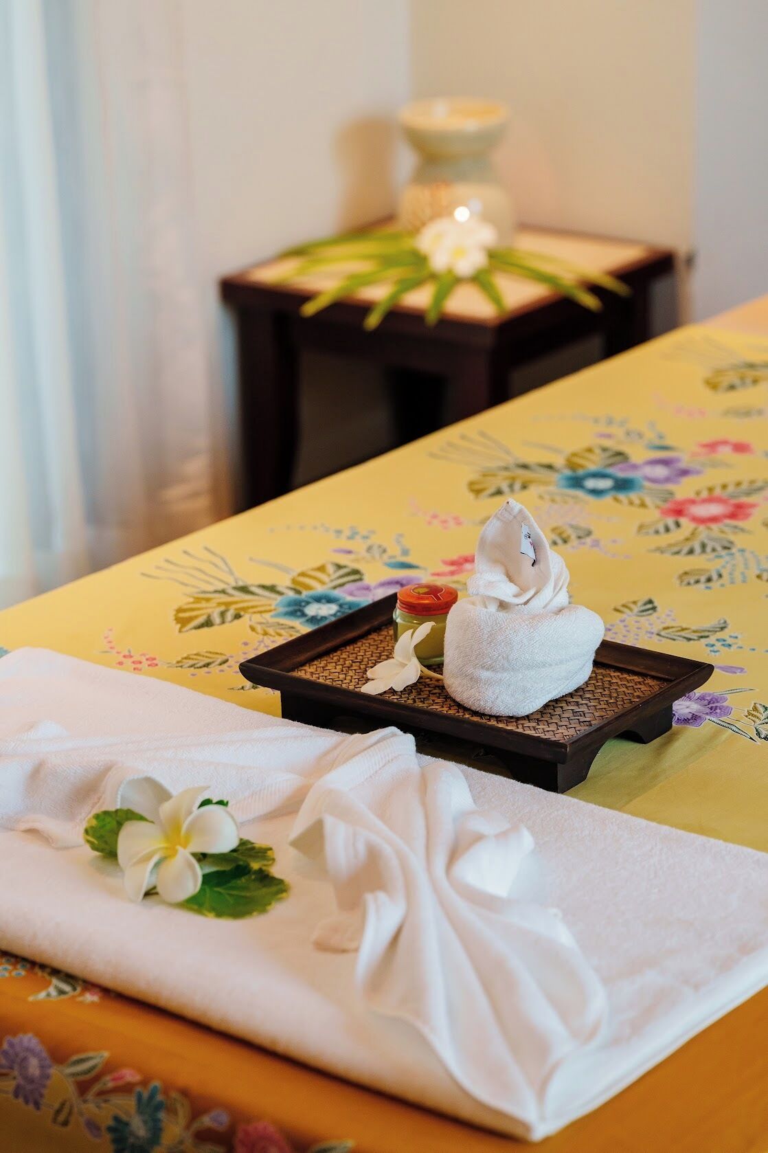 A neatly arranged spa area with a floral tablecloth, a towel, and a small candle on a side table.