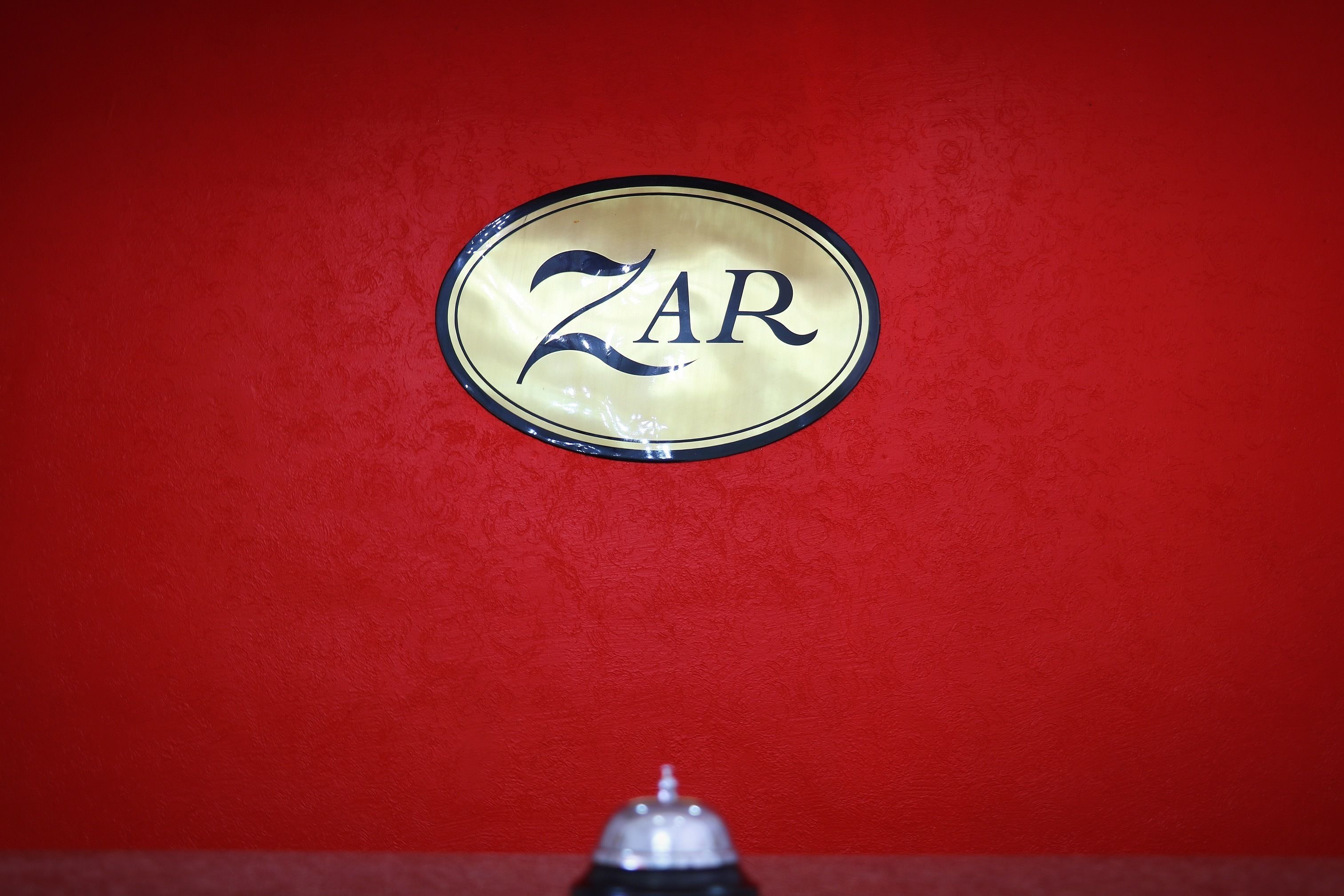 A red wall with a circular sign that reads "ZAR".