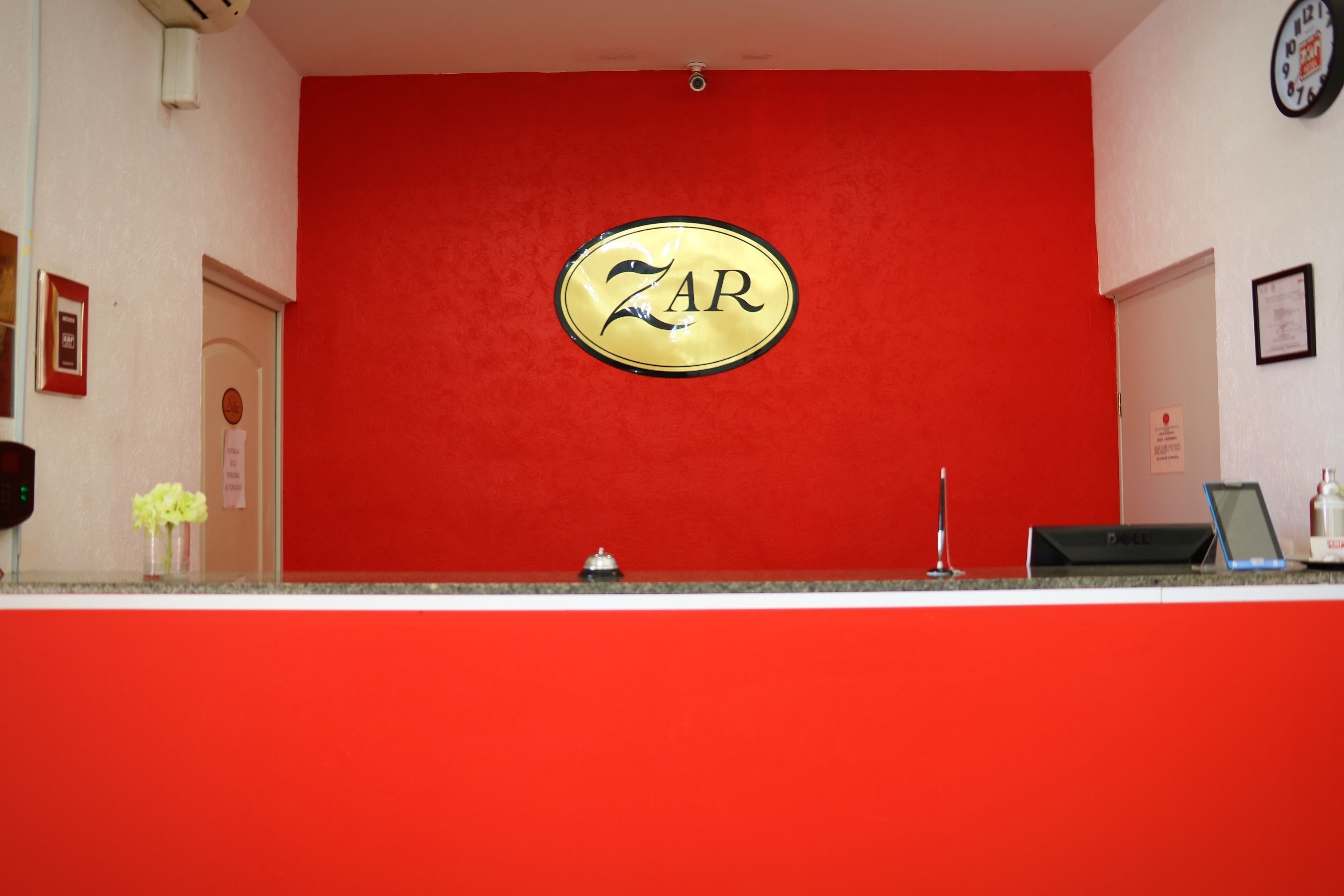 A reception desk with a red wall and a gold emblem that reads "ZAR".
