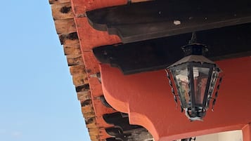 Un edificio de fachada roja, un arco blanco y una montaña al fondo.
