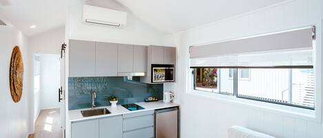 Una cocina moderna con gabinetes grises, lavavajillas integrado y una ventana con persianas.