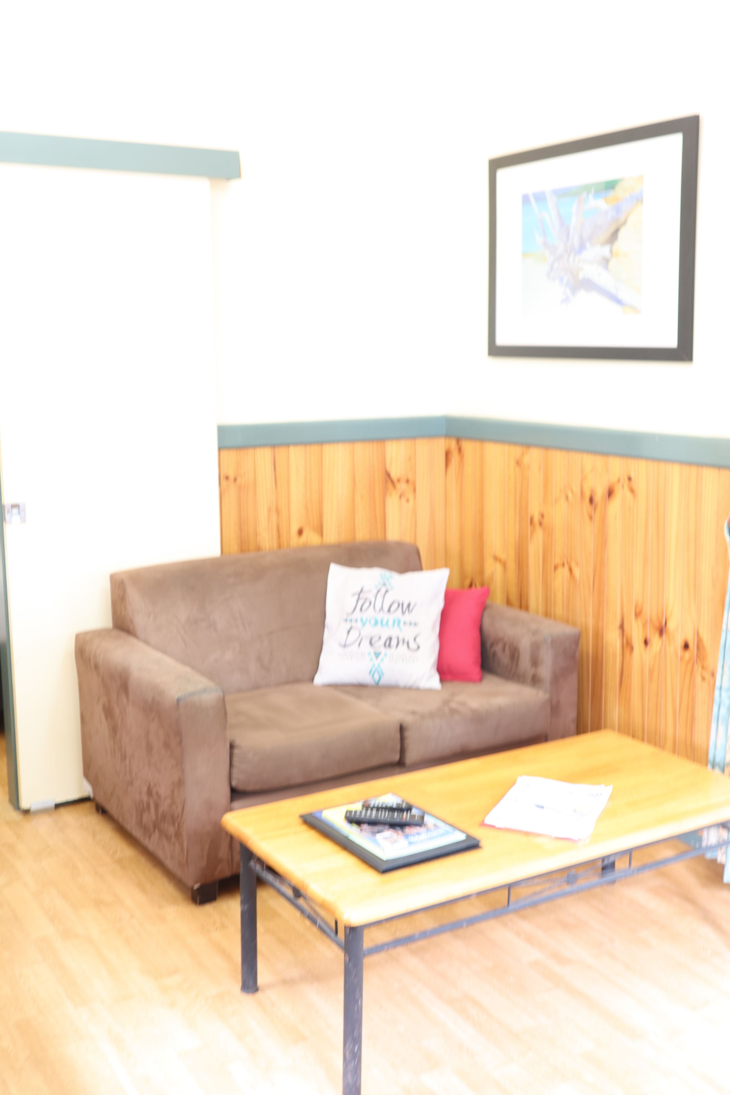 Um quarto com um sofá marrom, uma mesa de madeira e um quadro na parede.