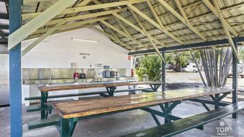 Un área de picnic techada con mesas y una barra de servicio de alimentos.