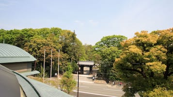 A traditional Japanese building with a curved roof, surrounded by lush green trees and a clear sky.