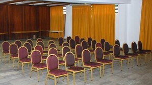 Een vergaderzaal met rijen stoelen en een podium.
