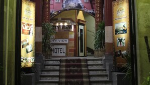 The entrance of City View Hotel with a sign in multiple languages, a staircase leading to the lobby, and a carpeted area. - City View Hotel (Cairo)