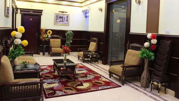 A lobby with a patterned carpet, wooden furniture, and floral arrangements. - City View Hotel (Cairo)
