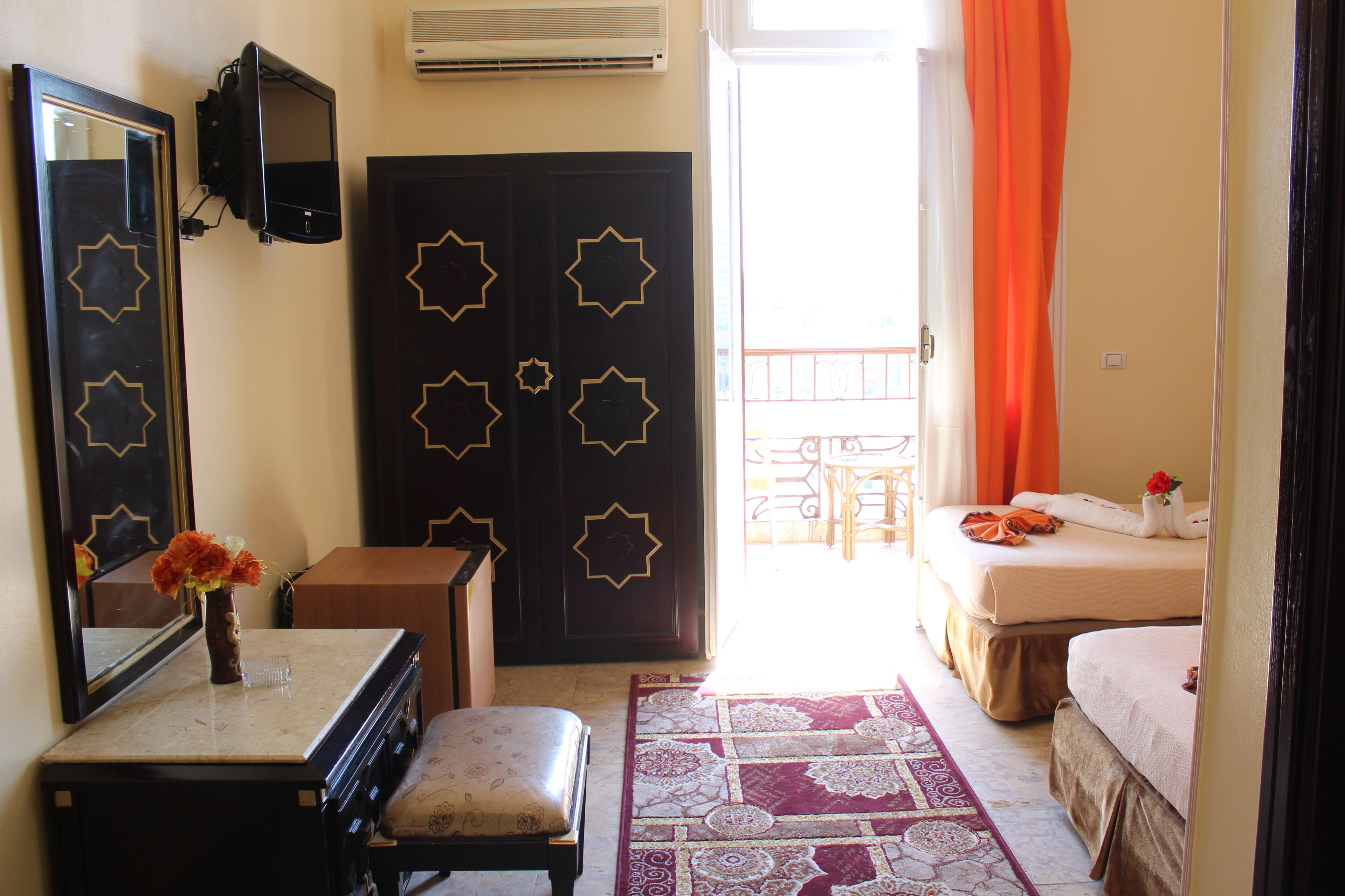 A hotel room with a bed, a desk, a chair, a dresser, and a mirror.