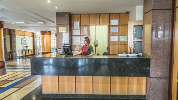 A reception desk with a receptionist, wooden paneling, and informational posters.